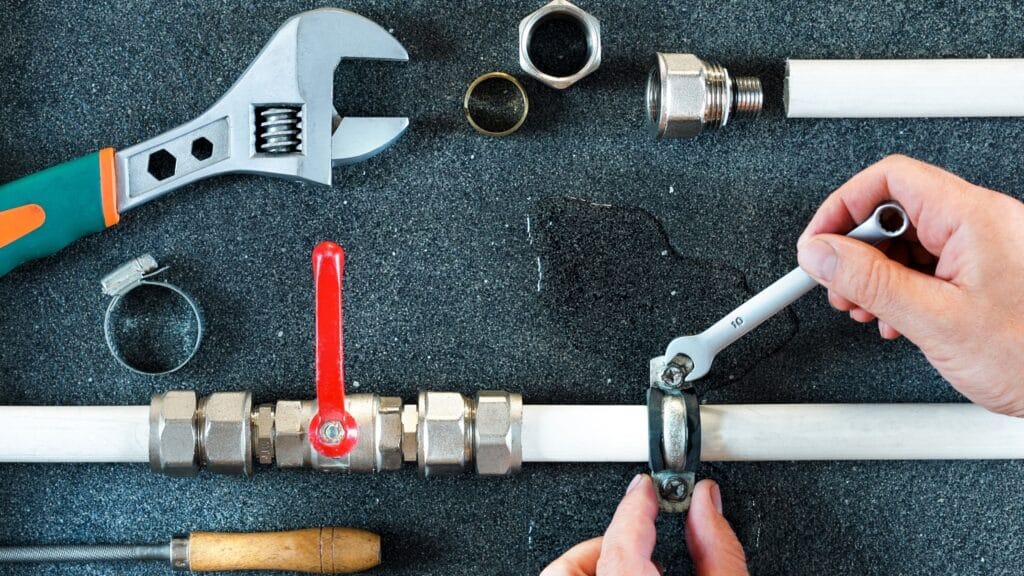 Plumber repairing a pipe valve with an adjustable wrench in Morgan Hill