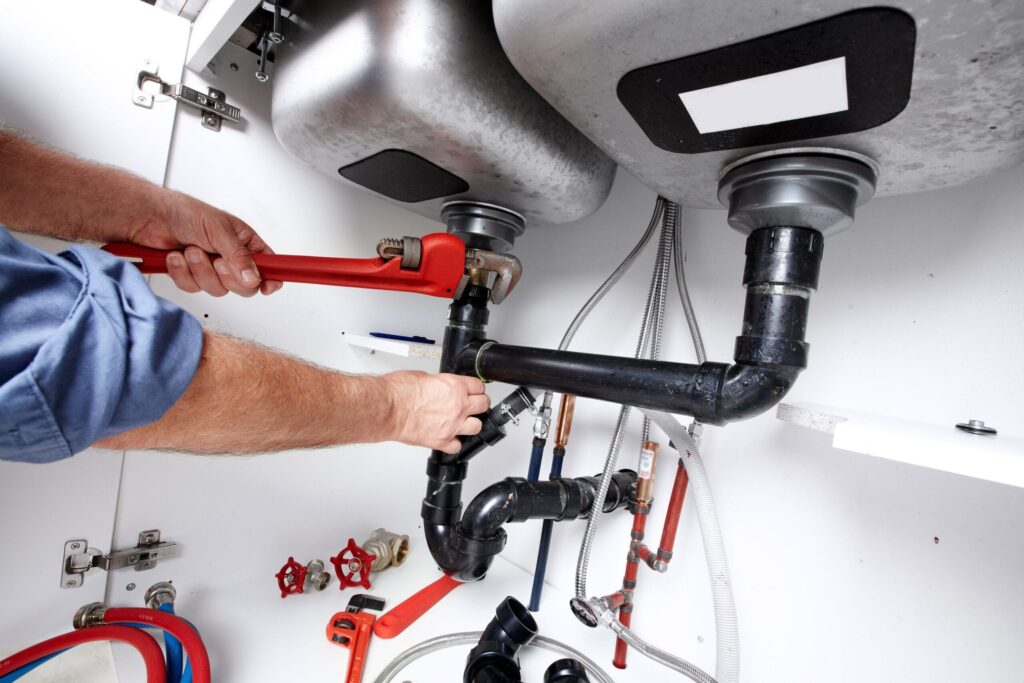 Plumber repairing drain pipes beneath a kitchen sink in Morgan Hill