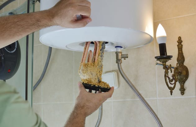Technician removing mineral buildup from a water heater in Morgan Hill